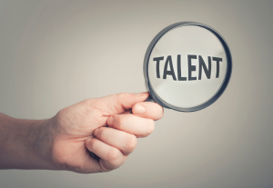 虫眼鏡で「TALENT」という文字を拡大する手