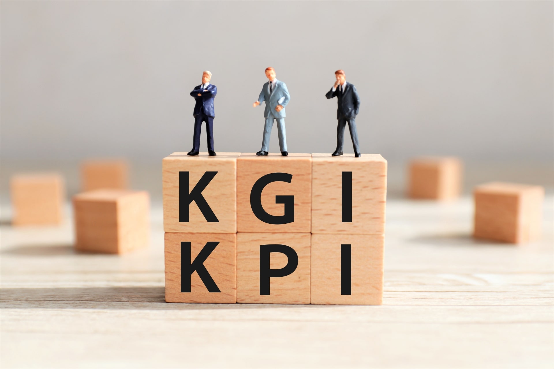 KGIとKPIの文字が書かれた木製ブロックとビジネスマンのミニチュア
