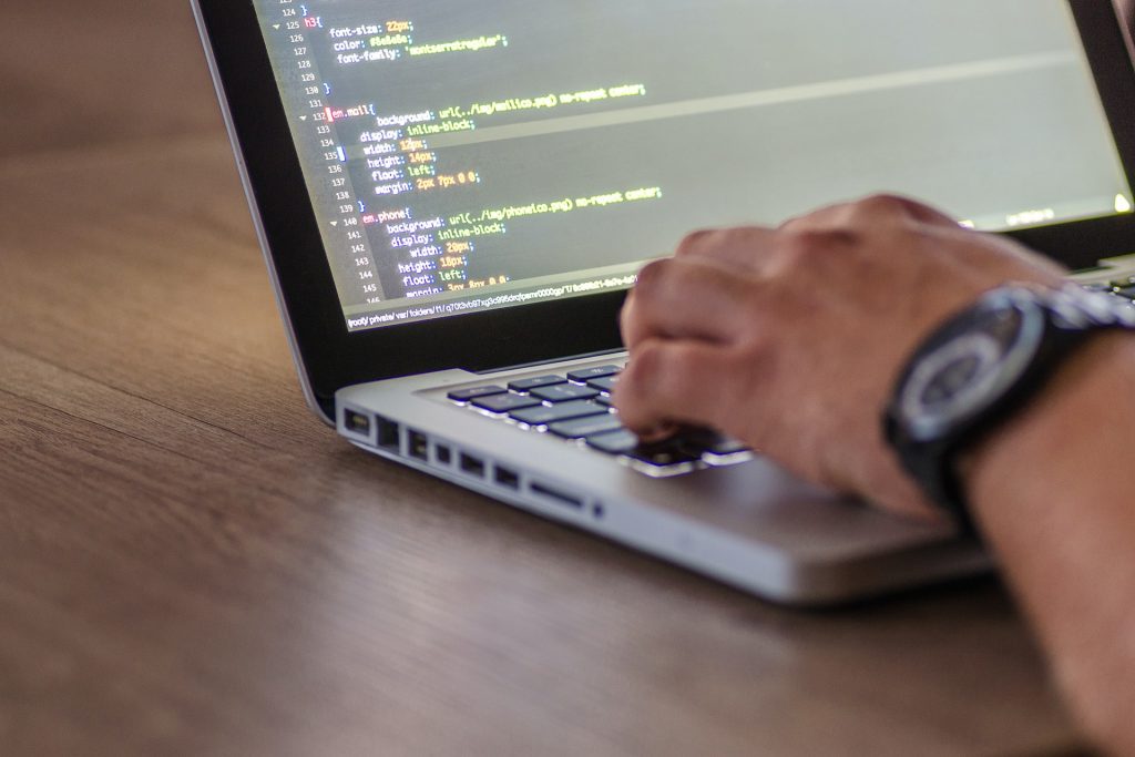 ノートパソコンでコーディングする人の手元。ウェブ開発やプログラミングのイメージ。