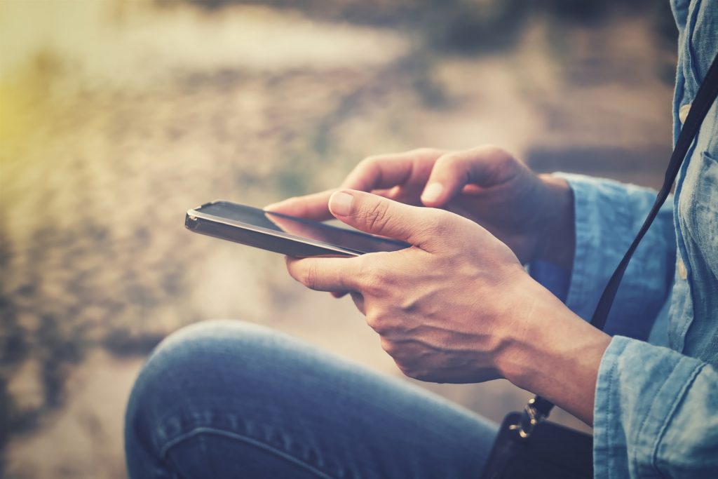 スマートフォンを操作する手。ホームページのスマホ対応の重要性。