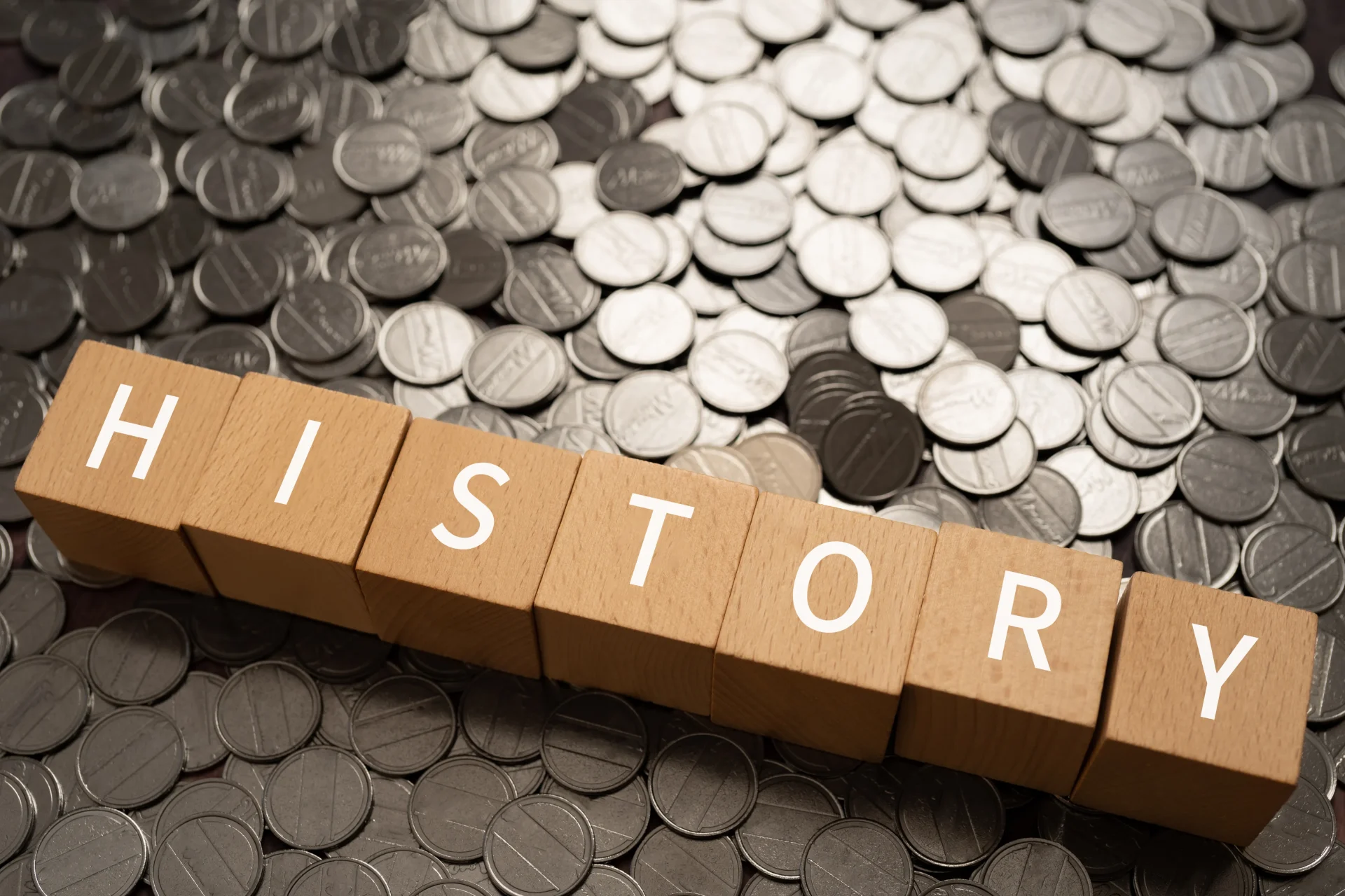 木製ブロックに「HISTORY」と書かれた文字と、背景には大量のコイン