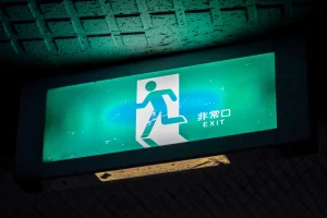 非常口EXITピクトグラム。緑色の非常口サインが暗闇で光っている。